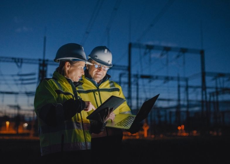 Man and woman working at an electrical substation at night