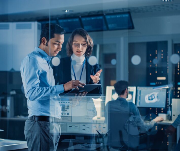 Two professionals reviewing workforce planning data and discussing clean tech skills and capability development within an organisation, highlighting the coordination required across functions to deliver the energy transition.